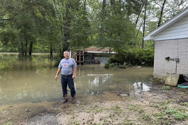 Miguel Flores Sr. stands in his flooded backyard.