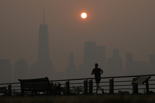 A man in Jersey City, New Jersey, runs in front of the sun rising over the lower Manhattan skyline on June 8, 2023, as smoke from Canadian wildfires blanketed the northeastern U.S. 